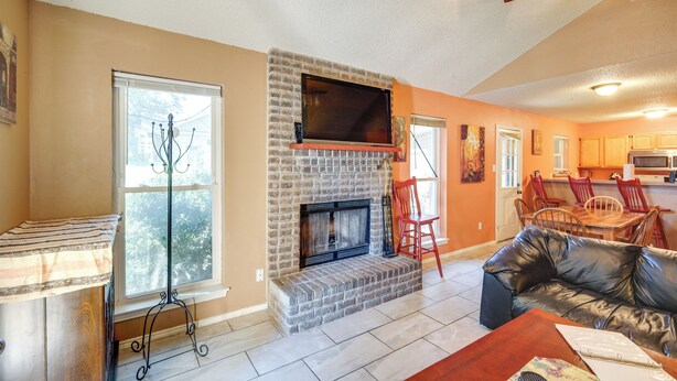 A living room with a fireplace, a leather sofa, a dining table with chairs, and a kitchen area in the background. - 4 Blocks to AT&T Stadium: 'Entertainment Central!' (Arlington)