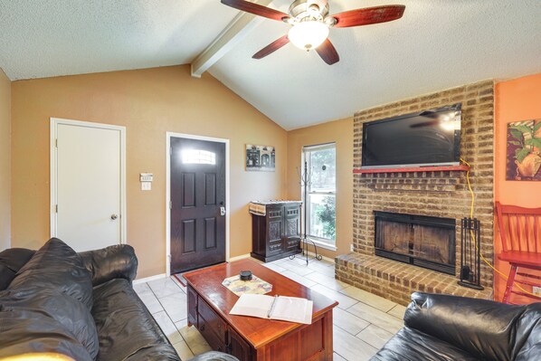 A living room with a fireplace, a ceiling fan, and a television mounted above it. - 4 Blocks to AT&T Stadium: 'Entertainment Central!' (Arlington)
