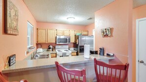 A kitchen with wooden cabinets, a microwave, a refrigerator, and a sink. There are two red chairs at the kitchen island. - 4 Blocks to AT&T Stadium: 'Entertainment Central!' (Arlington)