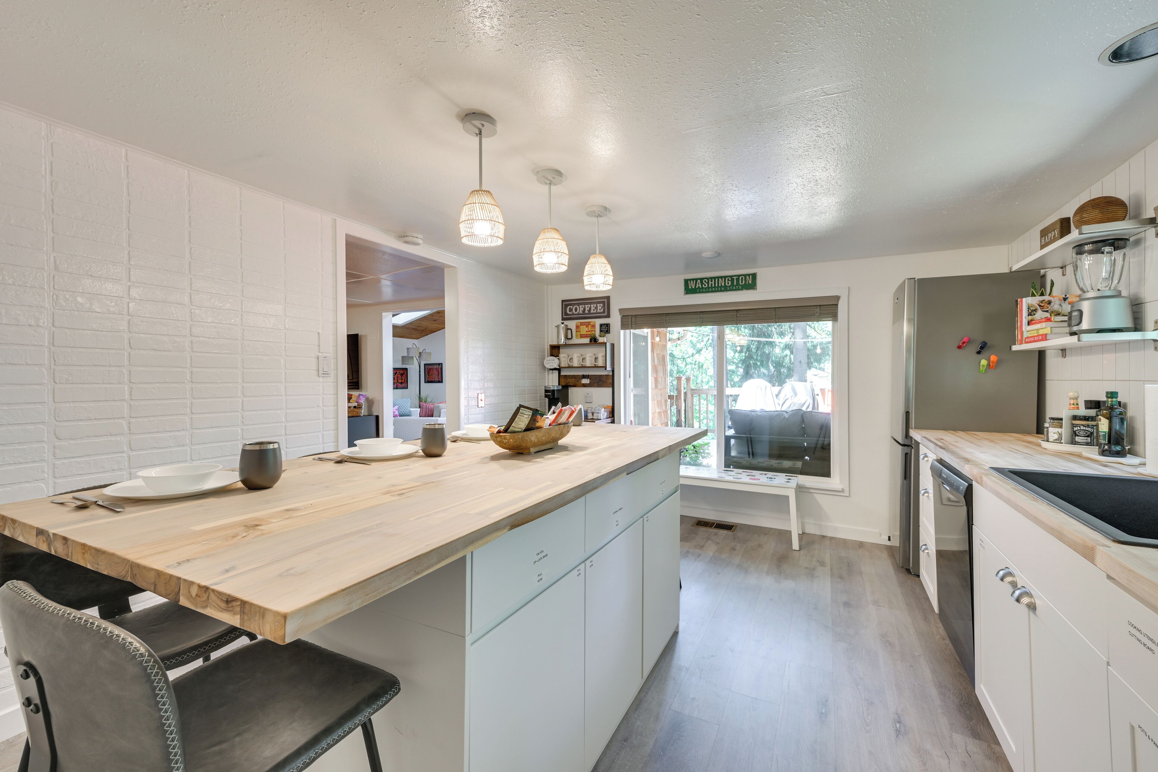 Une cuisine avec un îlot central en bois, des armoires blanches et des luminaires suspendus.