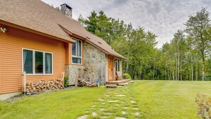 Una casa de piedra con fachada de madera, una chimenea de piedra y un porche de piedra.