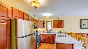 Una cocina con armarios de madera, un refrigerador de acero inoxidable, encimera de granito y una isla integrada con taburetes de bar.