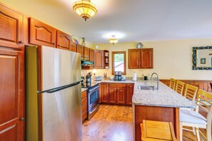 A kitchen with wooden cabinets, a stainless steel refrigerator, a granite countertop, and a built-in island with bar stools. - Game Room, Hot Tub! Year-Round Dover Retreat (West Dover)