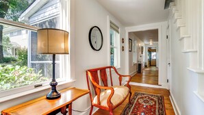 A hallway with a wooden desk, a chair, a rug, and a wall clock. - Charming Victorian Farmhouse on Historic Main St (Trappe)