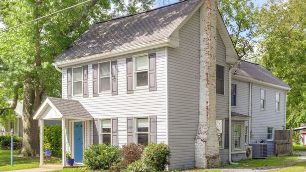 A two-story house with a porch, a small attached garage, and a well-maintained lawn. - Charming Victorian Farmhouse on Historic Main St (Trappe)