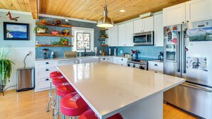 Una cocina moderna con una isla grande, electrodomésticos de acero inoxidable y taburetes de bar rojos.