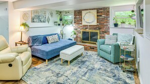 Una sala de estar con un sofá azul, un sillón color beige, una mesita con una lámpara y una chimenea.