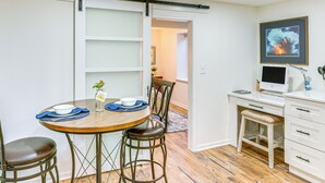 Un comedor con una mesa de madera, cuatro sillas y una puerta corrediza que da a una cocina.