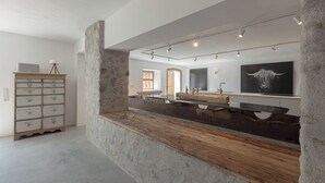 Une salle de bain moderne avec un mur d’accent en pierre, un meuble-lavabo en bois et un grand miroir.