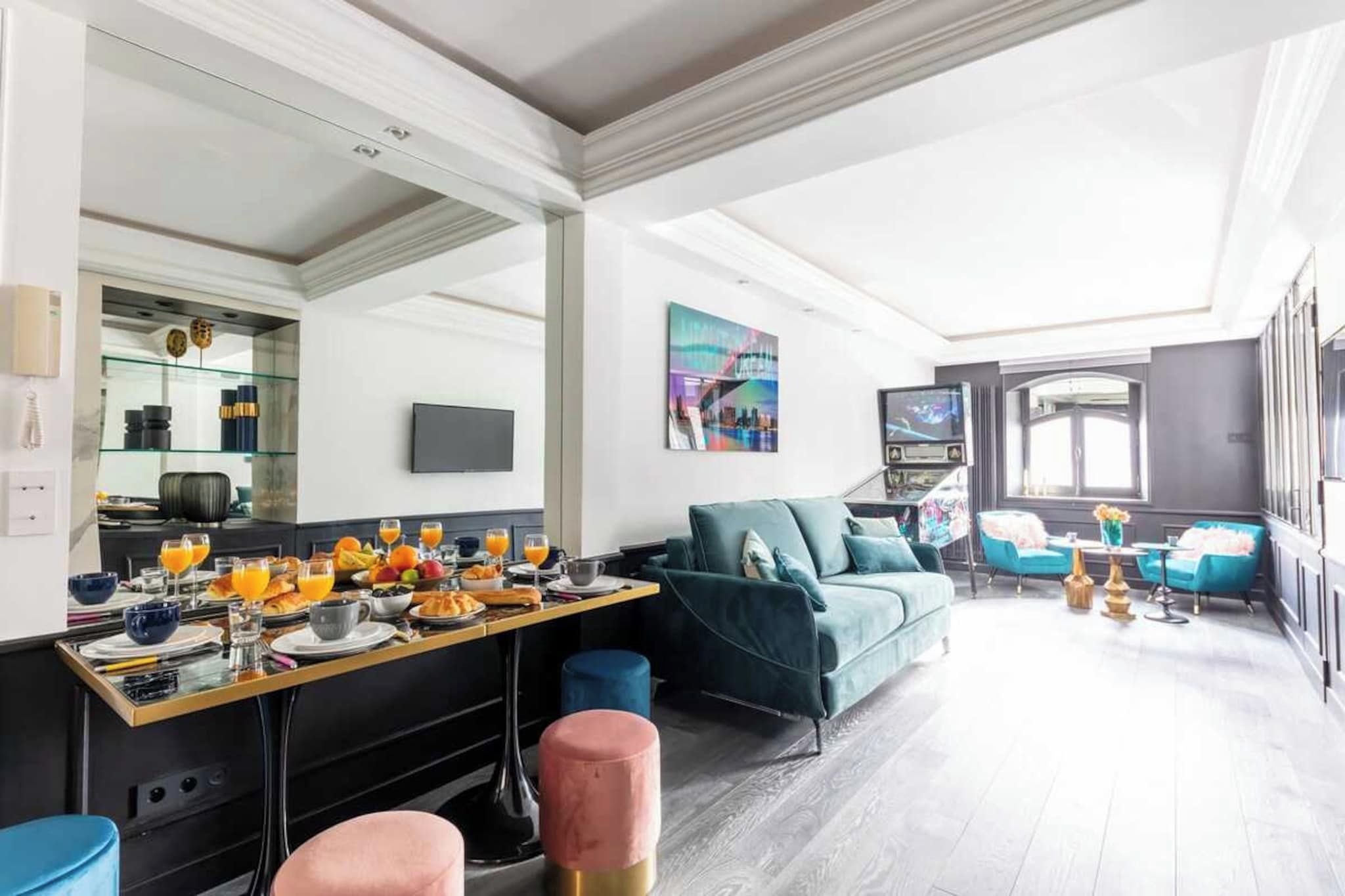 A modern living room with a dining area, a sofa, and a television.