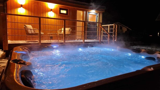 A hot tub with a wooden deck and chairs, surrounded by snow. - Soothing 4-bedroom villa in Bešenová (Bešenová)