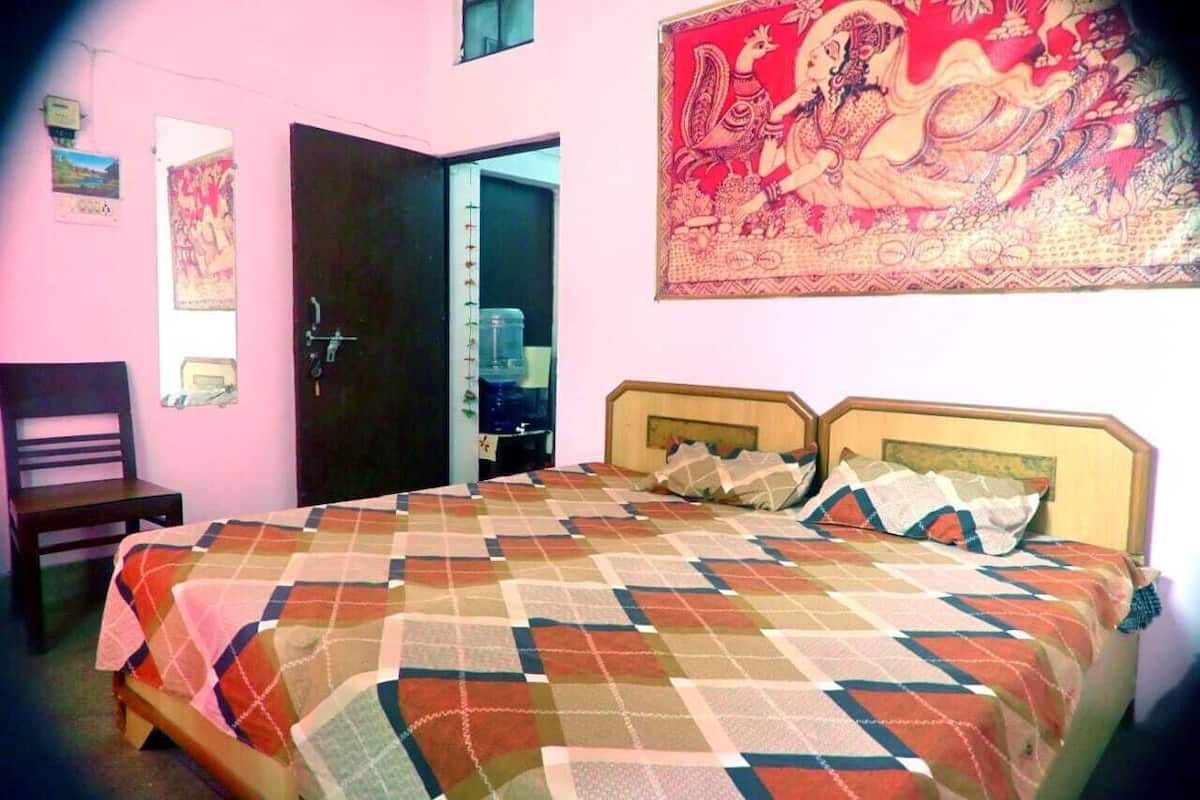 Ein Schlafzimmer mit einem Bett, einem Sessel, einer Tür und einer Wand mit einem Wandteppich.