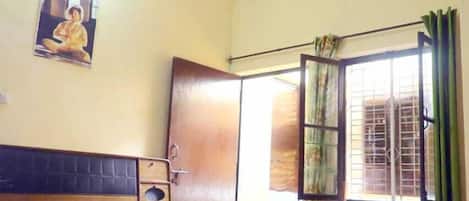 A bedroom with a bed, a ceiling fan, a window with curtains, and a door.