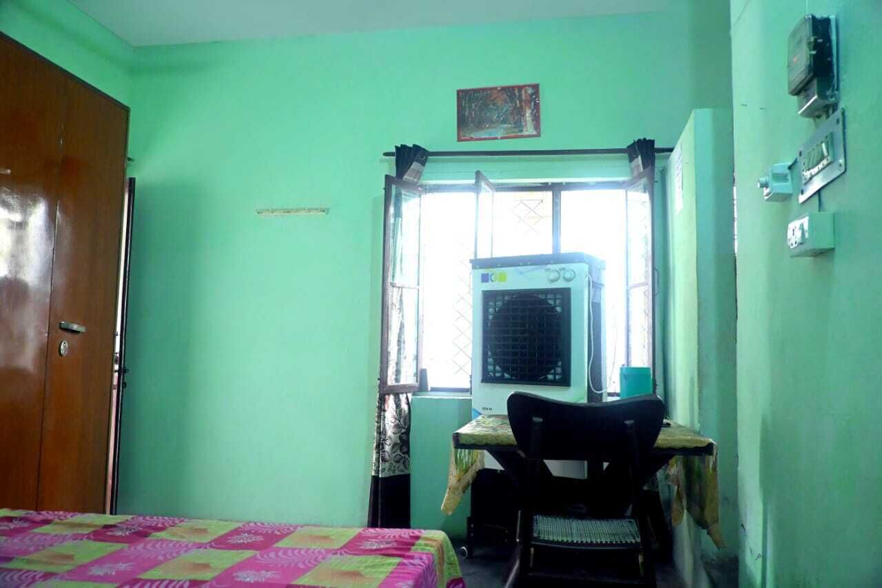 A room with a bed, a desk, a chair, a window with an air conditioner, and a door.