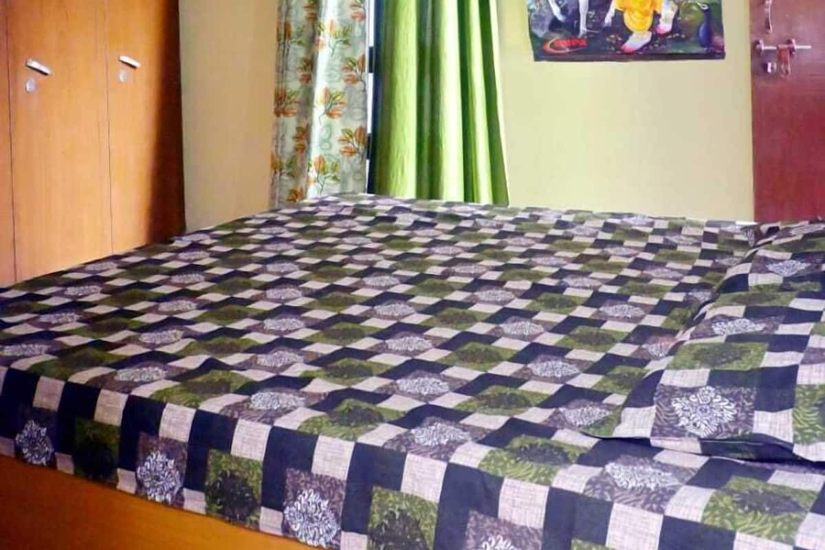 Ein Schlafzimmer mit Bett, Deckenventilator, Kleiderschrank, einem Gemälde und Vorhängen.