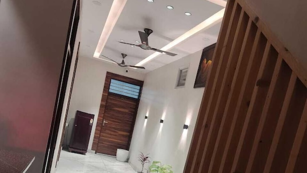 A modern hallway with a marble floor, a ceiling fan, recessed lighting, and a wooden door. - Hotel River View Panipat (Panipat)
