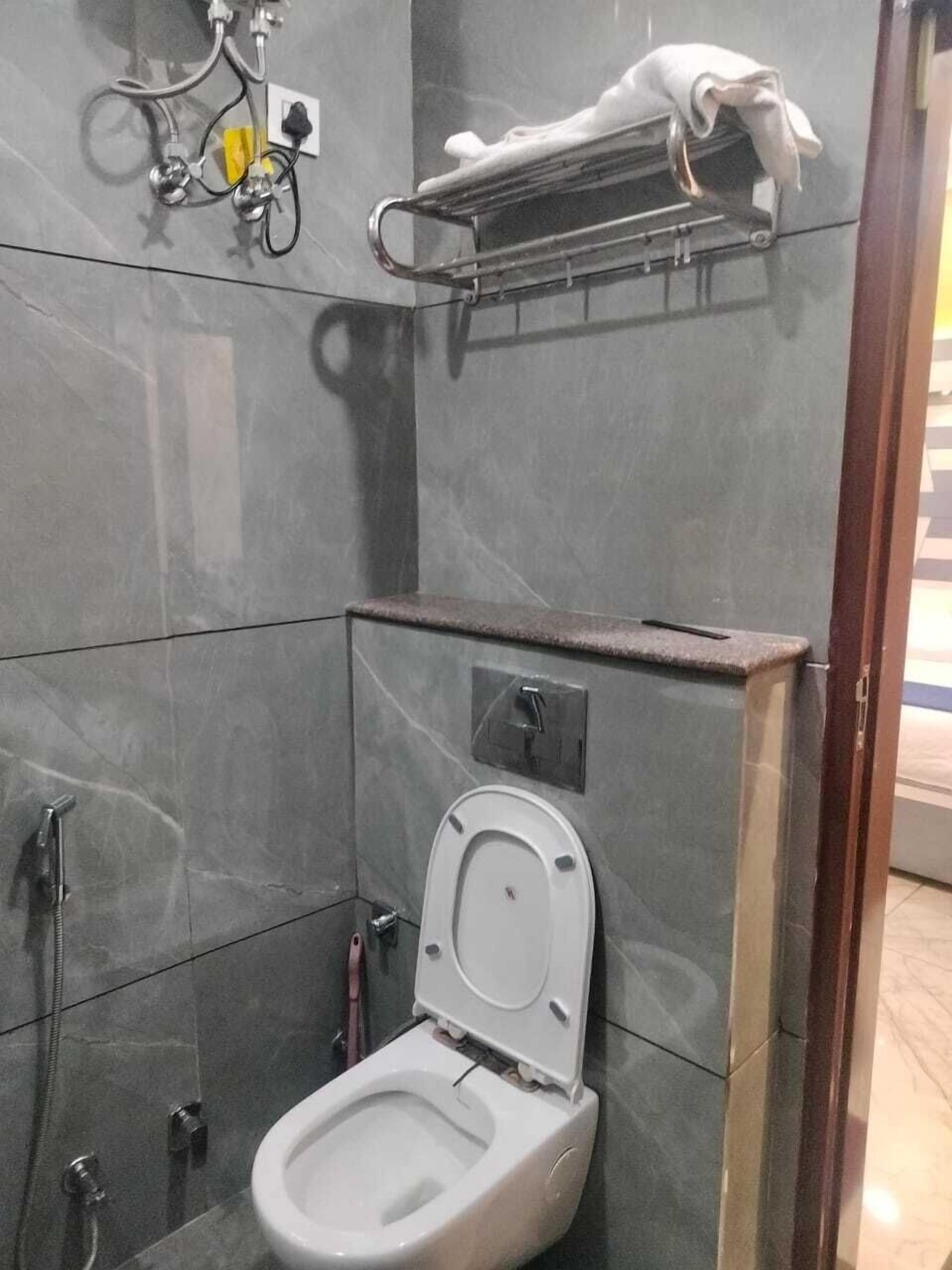 A compact bathroom with a toilet, a shower, and a towel rack.