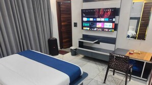 A hotel room with a bed, a desk, a chair, a TV, and a mirror. - Hotel River View Panipat (Panipat)