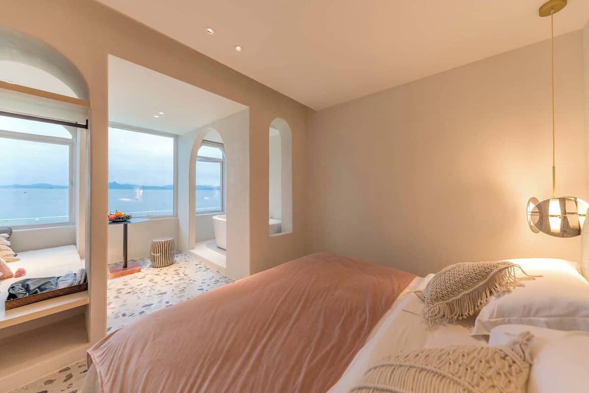 Une chambre avec un grand lit, une vue sur la mer et une petite table avec une chaise.