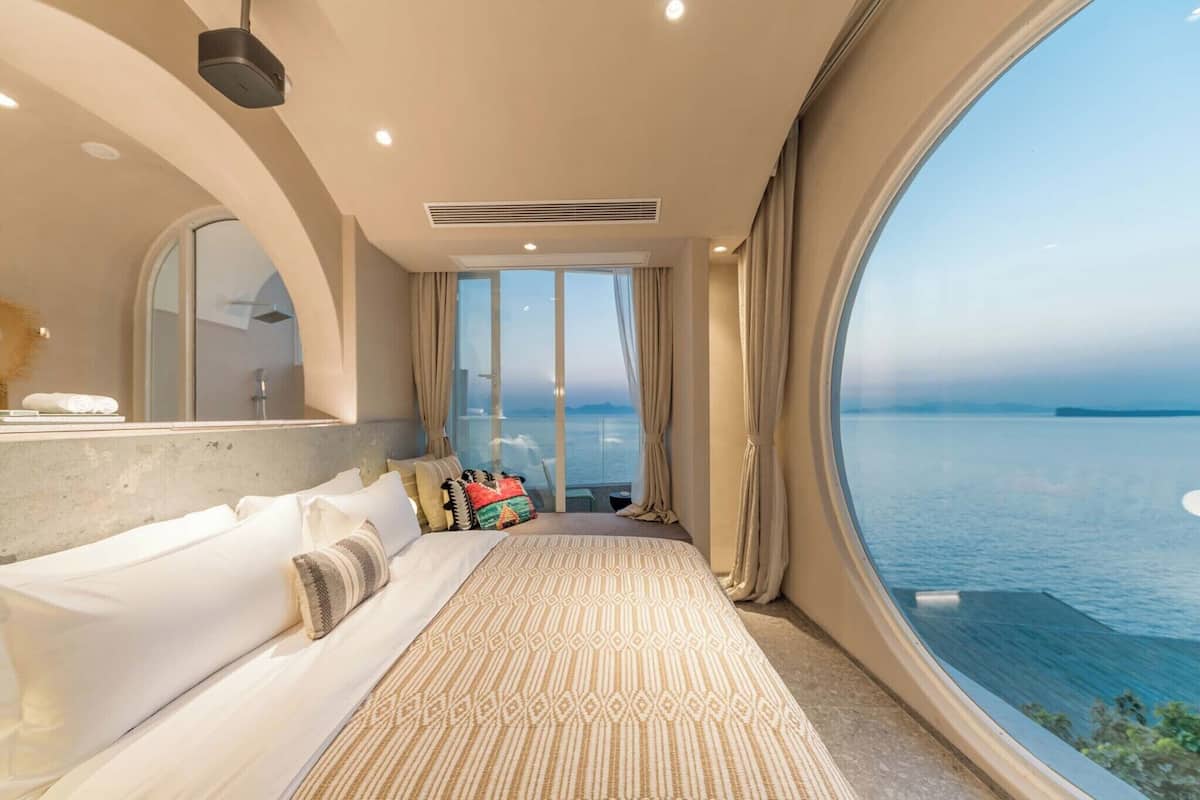 Une chambre moderne avec un grand lit, une vue sur la mer et une grande fenêtre.