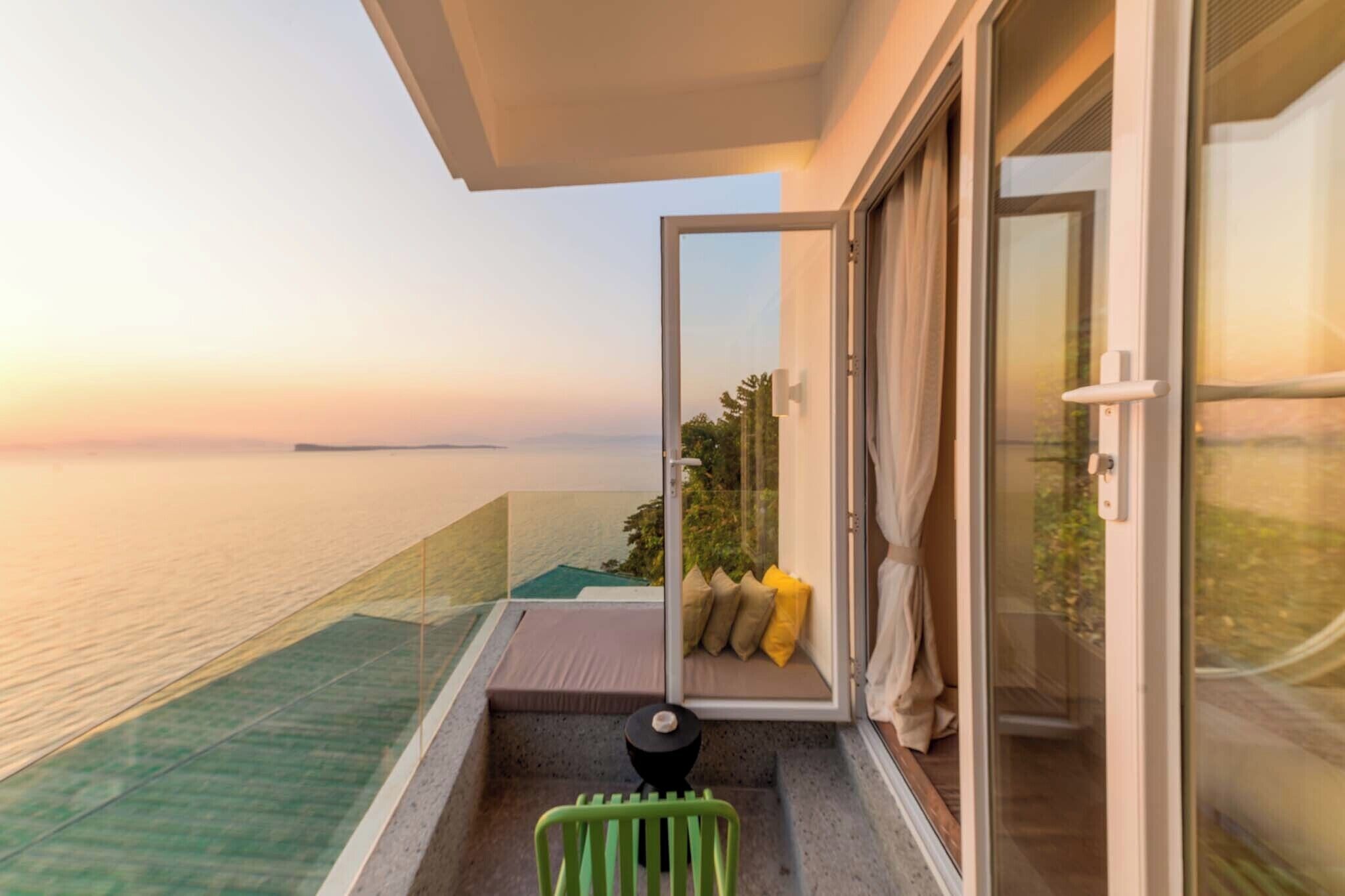 Un balcón con puerta de cristal que da a una habitación, una mesita y vista al mar.