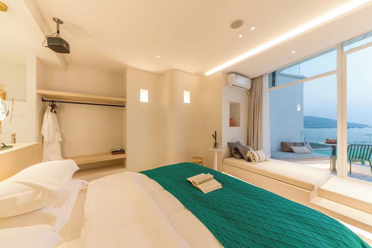 Une chambre d’hôtel avec un grand lit, un petit coin salon avec vue et un balcon équipé d’une table et de chaises.