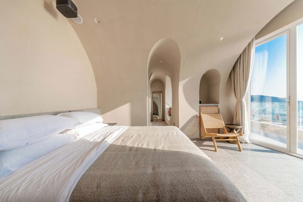 Une chambre d’hôtel avec un grand lit, une chaise et une vue sur la mer.