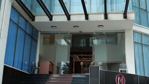 Un edificio moderno con fachada de vidrio, una escalera destacada que lleva a la entrada y un letrero del Hotel Crescent International.