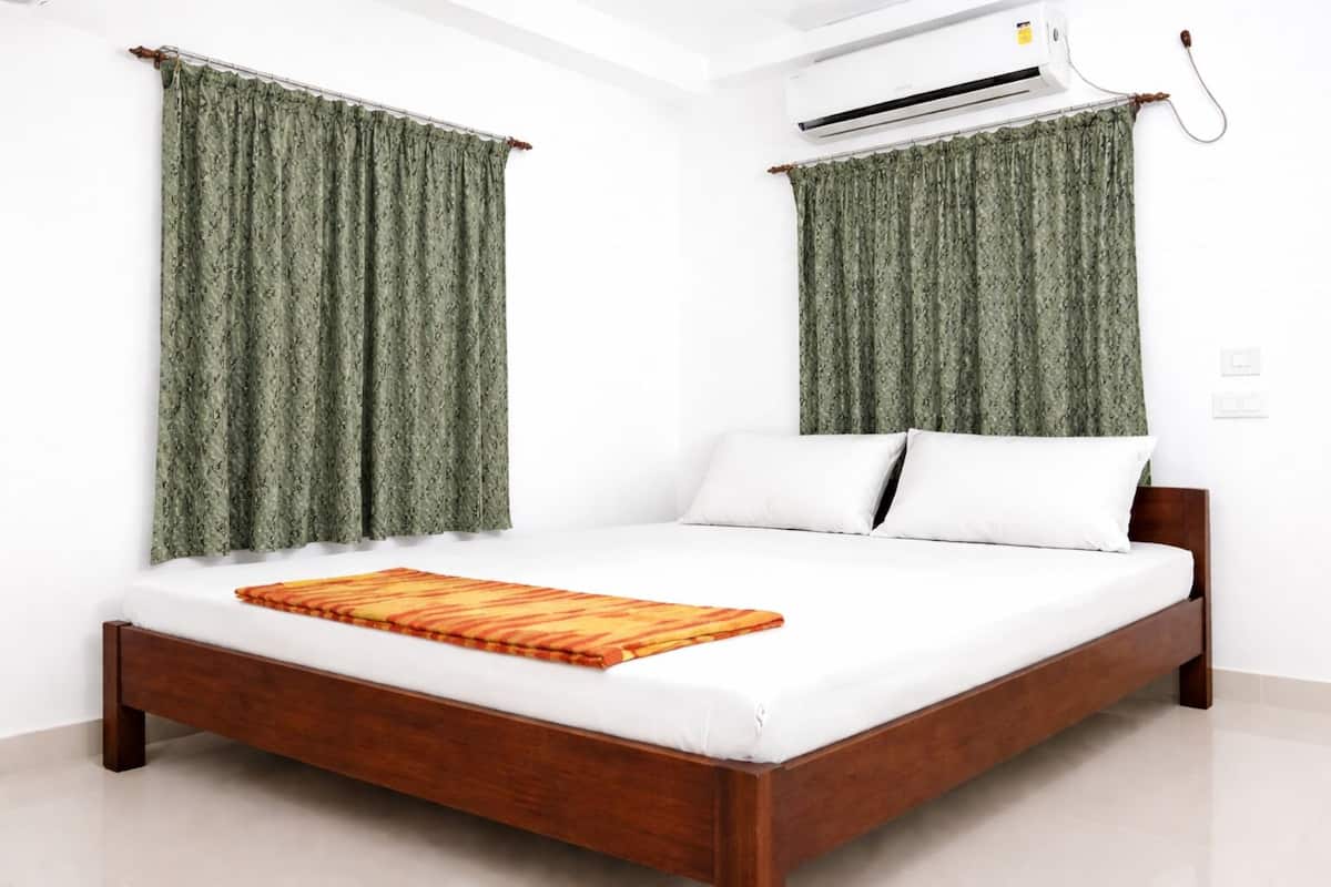 A single bed with a wooden frame, white bedding, and a patterned throw.