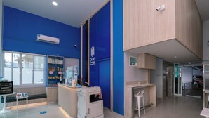 A reception area with a blue wall, a counter, a printer, and a security camera. - One Budget Hotel Chiangrai Soi Sawan (Chiang Rai)