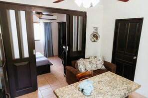 A room with a bed, a sofa, a table, and a door.
