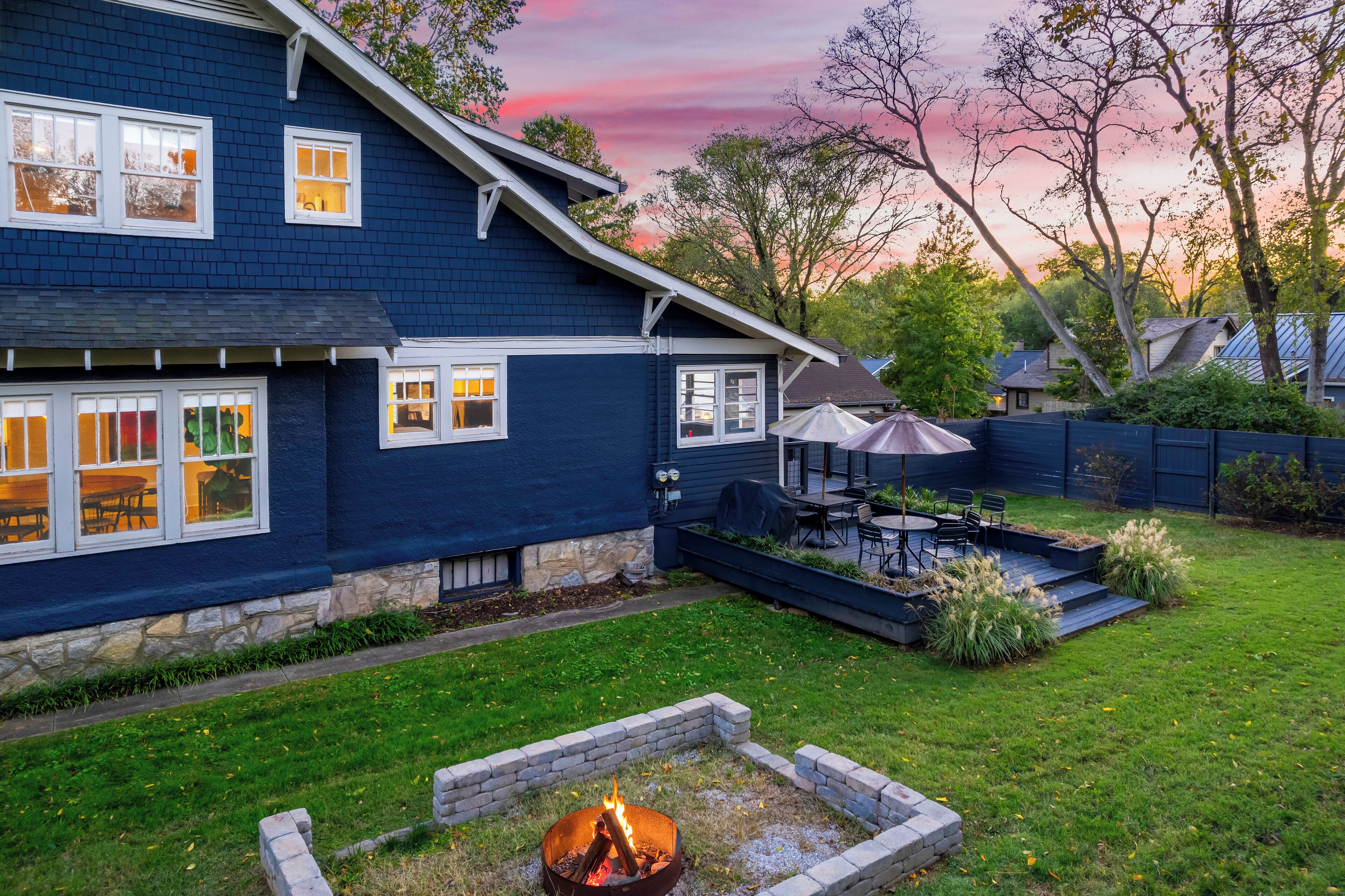 A house with a stone foundation, a fire pit in the backyard, and a patio area with outdoor furniture.