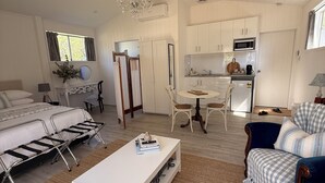 A spacious living area with a white sofa, a coffee table, and a dining table with chairs. - Hamptons style, studio retreat with light continental breakfast included (Strathalbyn)
