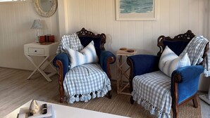 A room with two blue armchairs, a white table, a small side table, a mirror, and a painting on the wall. - Hamptons style, studio retreat with light continental breakfast included (Strathalbyn)