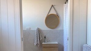 A bathroom with a toilet, sink, mirror, towel rack, and a shower curtain. - Hamptons style, studio retreat with light continental breakfast included (Strathalbyn)