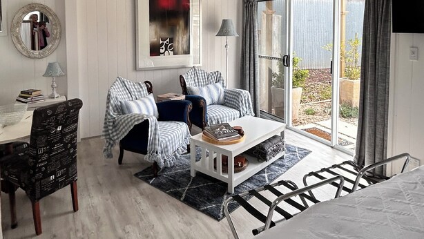 A spacious room with a chandelier, ceiling fan, and a large window with curtains. - Hamptons style, studio retreat with light continental breakfast included (Strathalbyn)