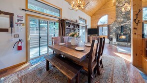 A spacious dining area with a wooden table, benches, and a stone fireplace. - Forest Views, Hot Tub & Tahoe Donner Access | Alpenglow Chalet by AvantStay (Truckee)