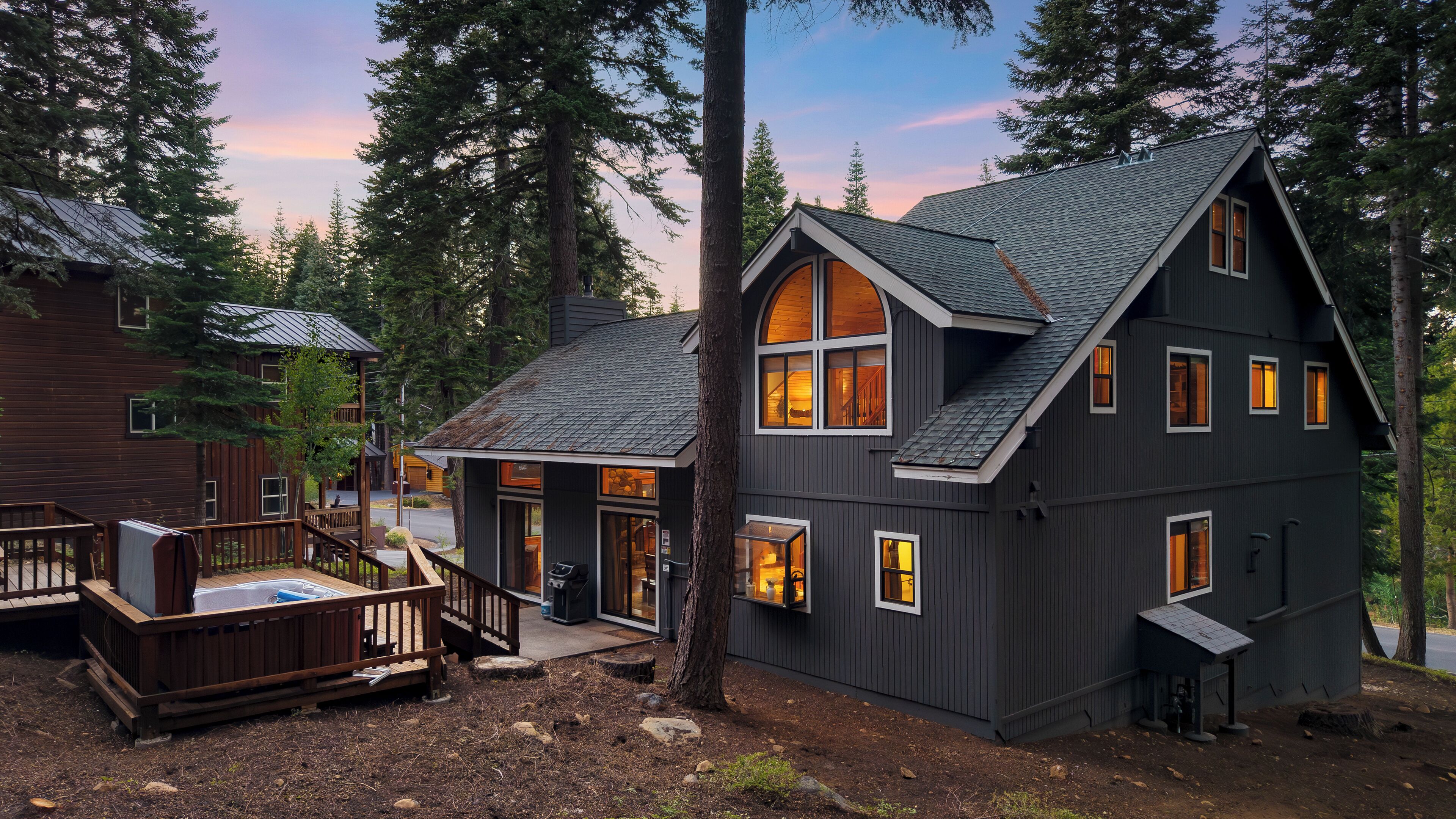 A cabin with a deck, large windows, and a sloped roof.
