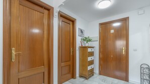 A hallway with wooden doors, a marble floor, and a small plant on a cabinet.