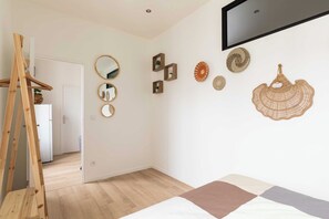 A bedroom with a bed, wooden ladder, and wall decorations including mirrors and woven art pieces. - DIFY Apartment 2BR/4P - Paul Bert/Part-dieu (Lyon)