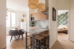 A modern kitchen with a marble countertop, wooden cabinets, and a dining area with bar stools. - DIFY Apartment 2BR/4P - Paul Bert/Part-dieu (Lyon)