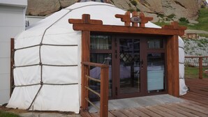 A wooden structure with a white canvas covering, a wooden door, and a sign with the number 1034. - Premium Bolor Resort Terelj (Ulaanbaatar)