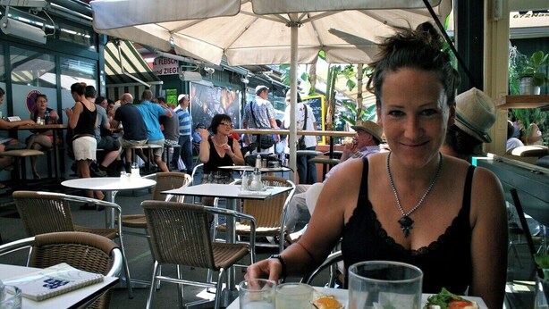 Un restaurante con terraza, sillas de mimbre y mesas con bebidas y platos de comida.