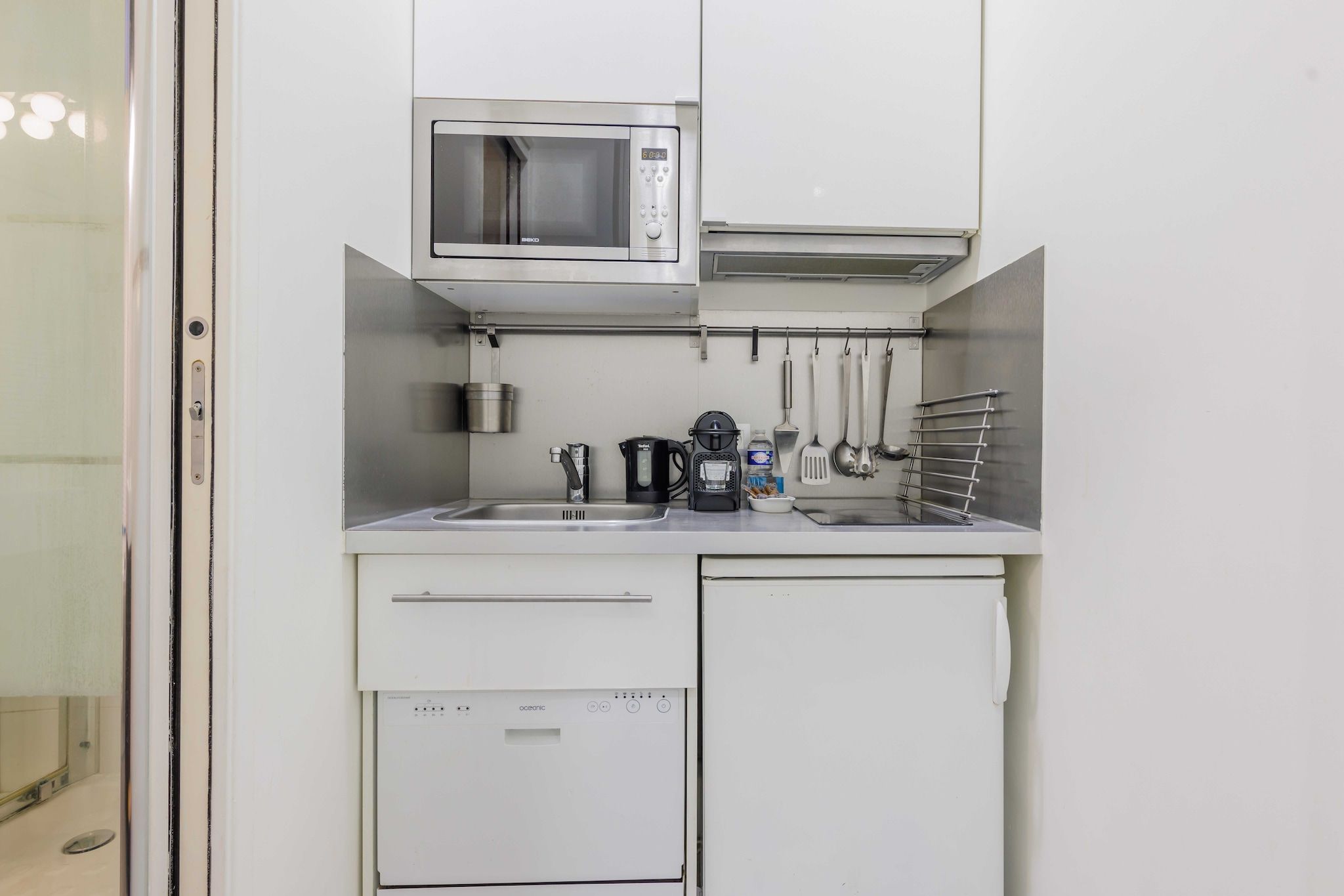 A compact kitchenette with a microwave, coffee maker, and a dish rack.