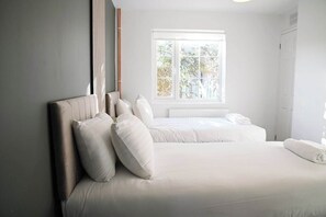 Une chambre à coucher avec un lit, des oreillers, une fenêtre et un radiateur.