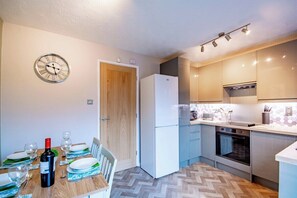 A compact kitchen with a refrigerator, oven, microwave, and a dining area with a table set for two.