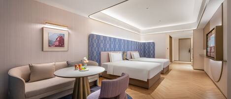 A modern hotel room with a sofa, a round table, a bed, and a chair.