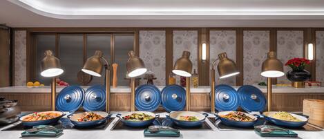 A buffet setup with multiple serving stations, blue serving dishes, and gold-colored lamps.