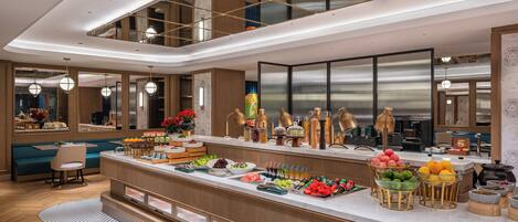 Una cocina moderna con barra de desayuno, muebles de madera y una variedad de frutas y bebidas.