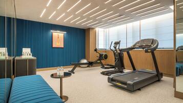 A fitness room with exercise equipment, a blue sofa, and a wall-mounted picture.